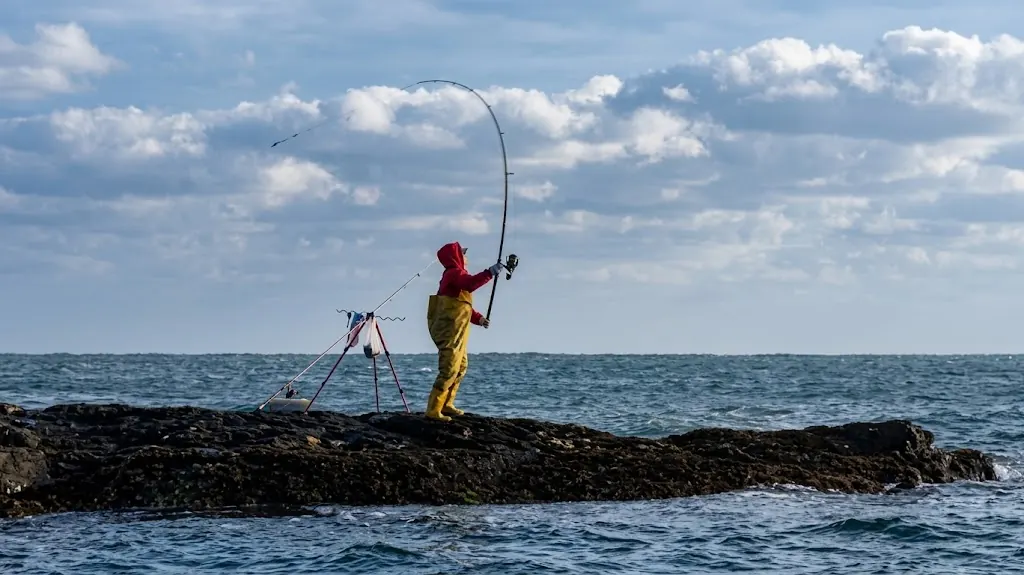 Anglers fishing the rocks where a river meets the sea, a classic river estuary scene.